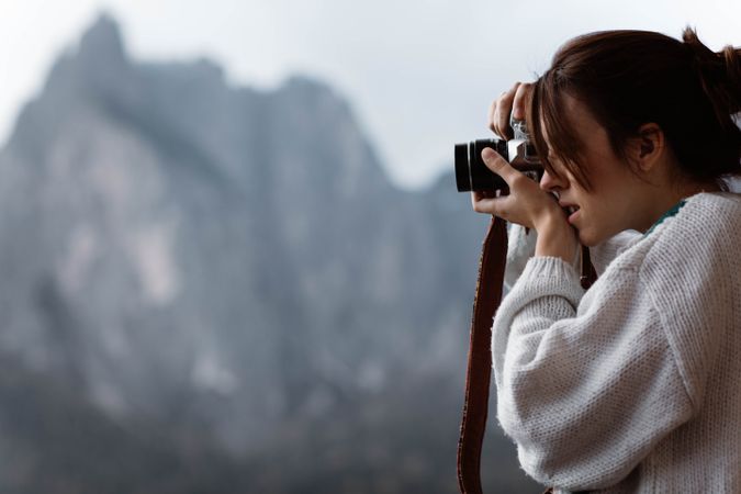 Female photograph in casual wear taking photo from opened window