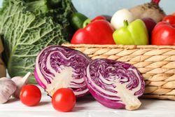 Wicker basket and vegetables on wooden background, close up