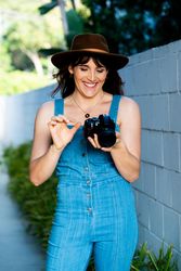 Smiling female photographer looking down at camera during shoot