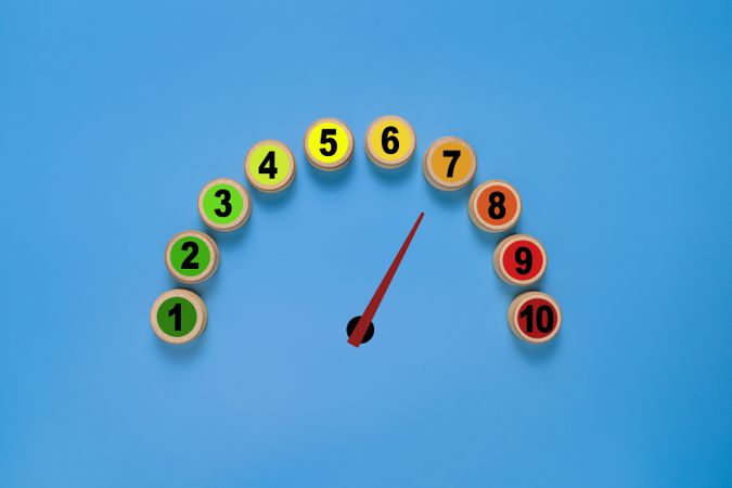 risk level meter indicator from low to high with 1 to 10 scale numbers on wooden blocks. isolated on blue background. concept of risk management