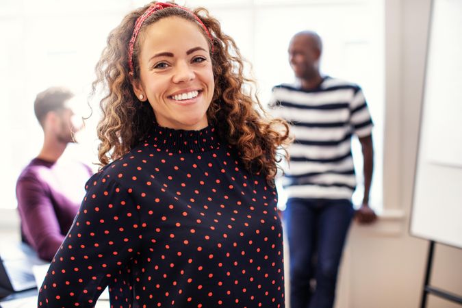 Woman with curly hair standing proudly in office