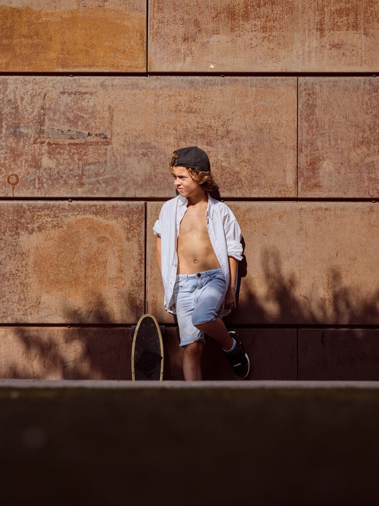 Stylish preteen skater standing outside building