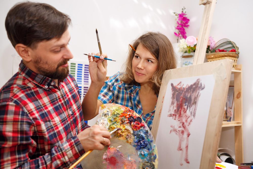 Female jokingly tries to paint the face of her friend in art class