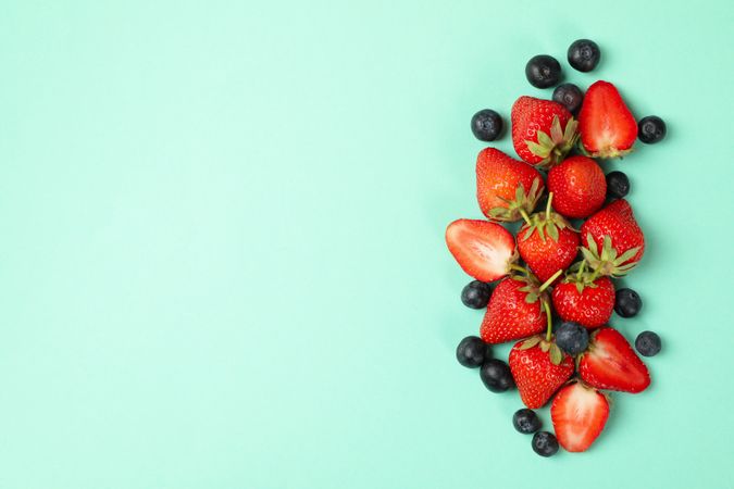 Tasty red strawberry and blueberry on mint background, top view