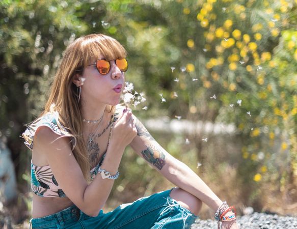 woman blowing on dandelion