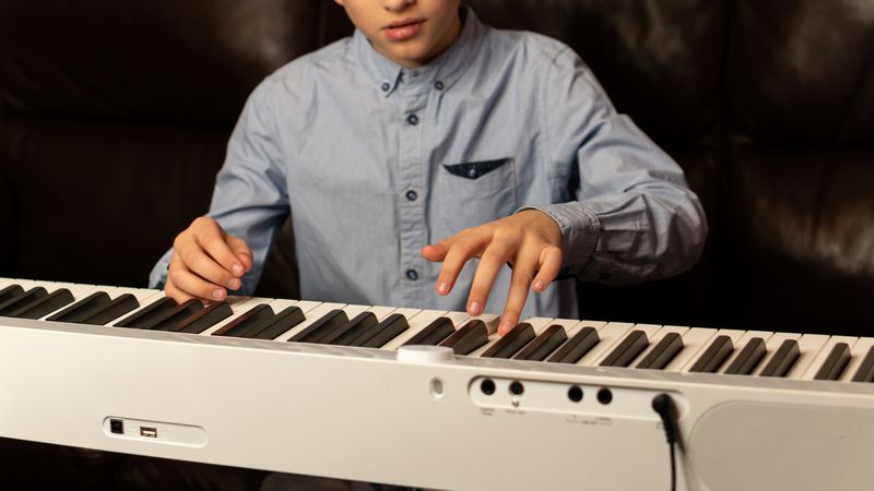 Boy practicing piano on white keyboard