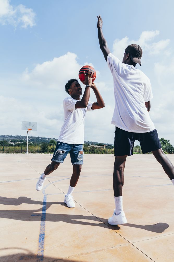 Black men playing basketball in bright day
