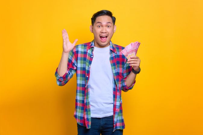 Asian man excited about money he won in studio shoot