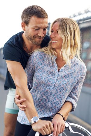 Man embracing woman from behind as she sits on a bike