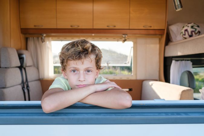Calm boy looking at camera through camper window