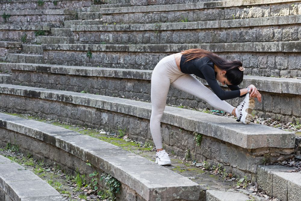 Slim woman in sportswear stretching legs before yoga practice