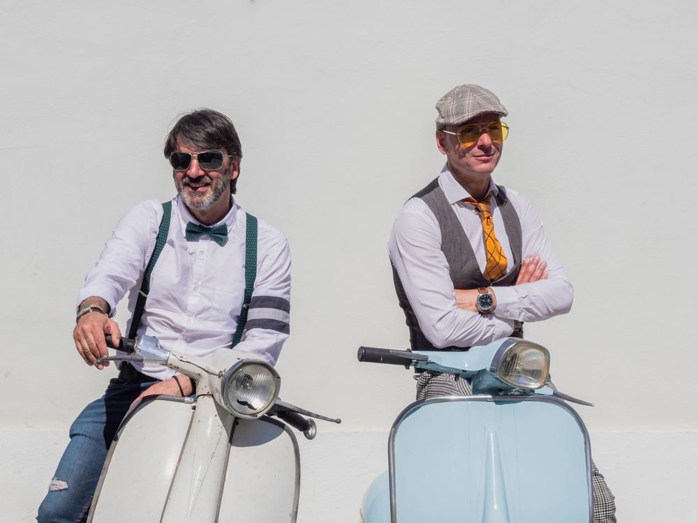 Trendy men sitting on vintage scooters
