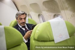 Male using smart phone with ear buds in flight 0P7jNb