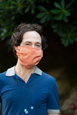 Portrait of happy man looking at camera wearing red mask outside