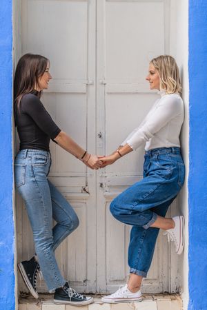 Positive women holding hands in doorway
