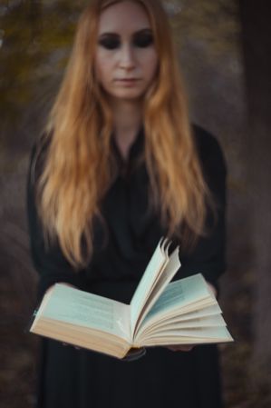 Woman in dark dress holding an open book