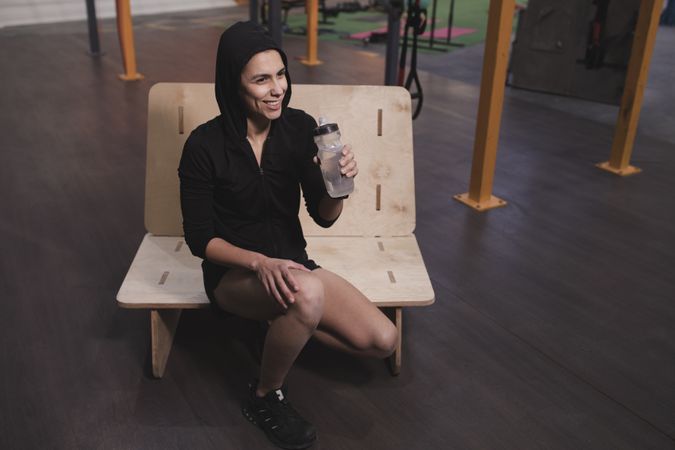 Smiling woman with bottle of water in gym
