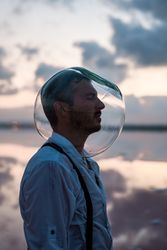 Man with fish tank on head standing at seashore