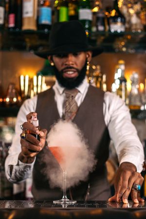 Stylish Black bartender preparing a cocktail with a smoke bubble in a traditional cocktail bar