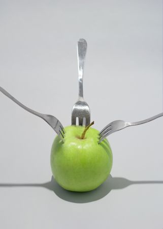 Green apple stabbed with many forks