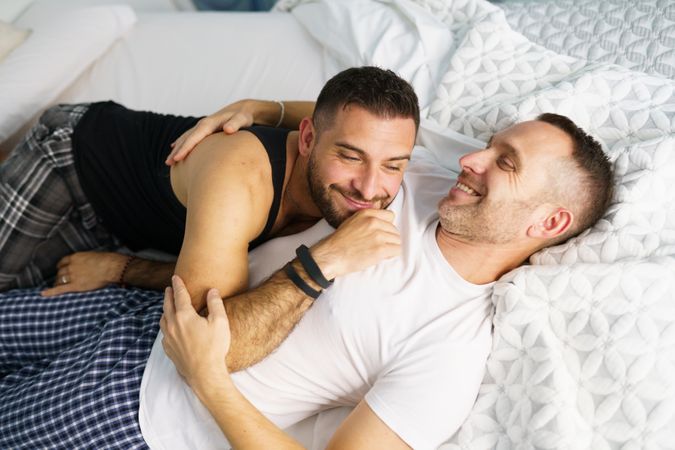 Two men smiling and lying together in bed