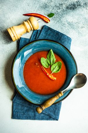 Top view of traditional Spanish soup of tomato gazpacho with basil garnish and peppermill