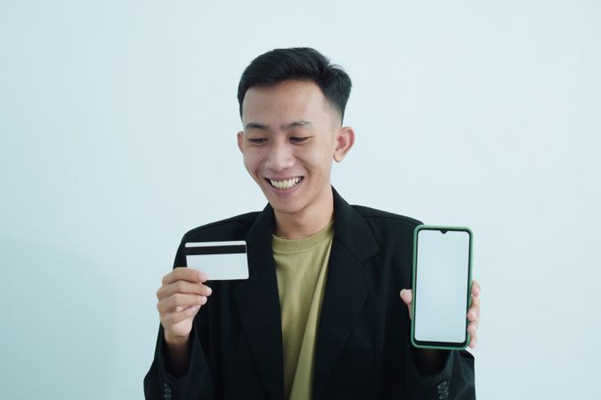 Businessman wear suit with t-shirt holding blank credit card in studio shoot