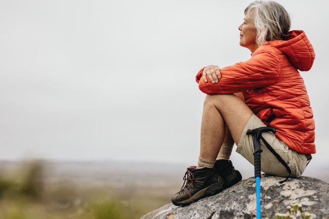 Mature woman sitting relaxed on a rock after her hike