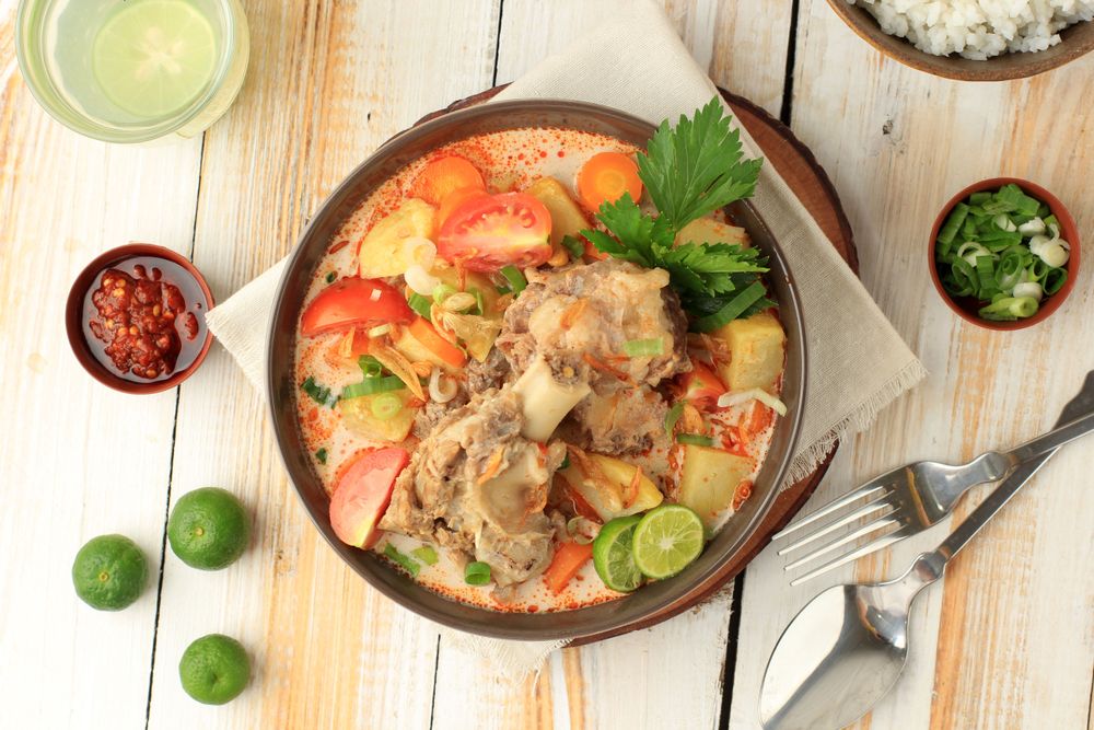 Top view of bowl of Indonesian beef stew served on the bone with rice