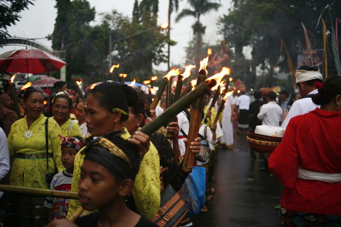 Group of Indonesian Hindu women with lit up torches marching during Nyepi day