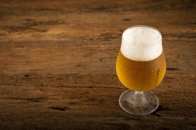 Glass full of cold beer on the wooden table