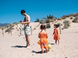 Father and daughters playing with kite on beach
