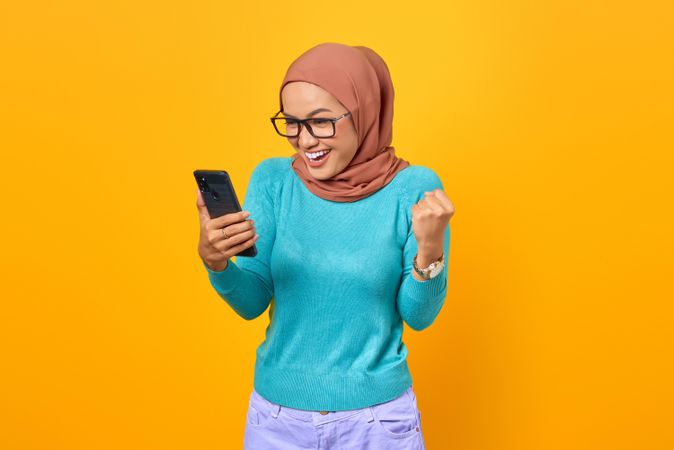 Muslim woman taking video call on her phone celebrating a victory