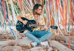 Man sitting under tree playing guitar