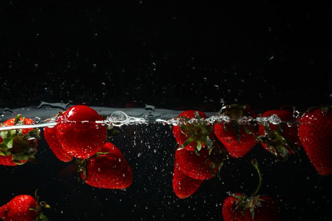Side view of sparkling water on dark background with strawberries