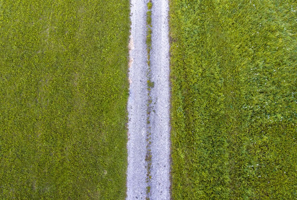 Drone aerial view with green grass fields and countryside road