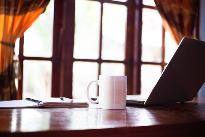 No people in living room with book, laptop and cup of coffee