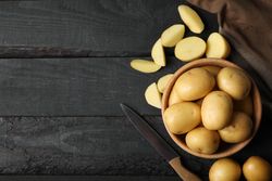 Top view of bowl of potatoes with potato wedges on dark kitchen counter, copy space