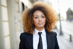 Serious female in suit walking down street outside