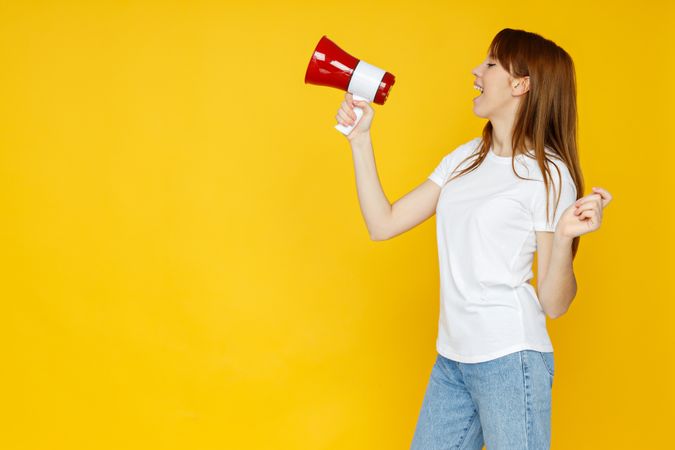Concept of people, woman with megaphone on yellow background