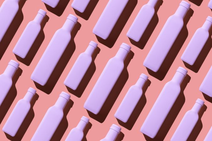 Light pink painted glass bottles laying on pink background