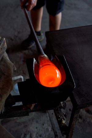Crop man with molten glass on blowpipe