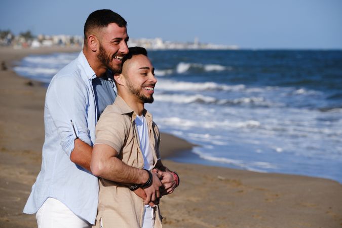 Happy gay couple hugging on seaside