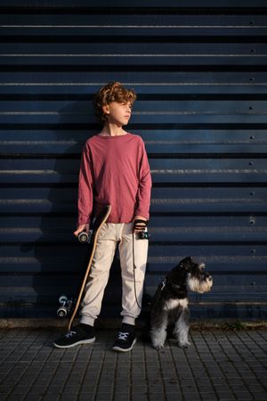 Boy with dog and skateboard on street