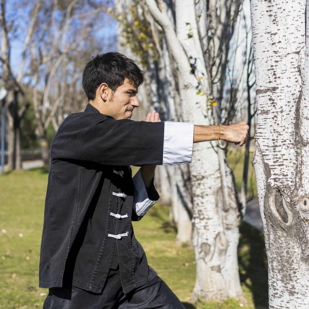 Young athletic martial arts fighter practicing kicks in a public park