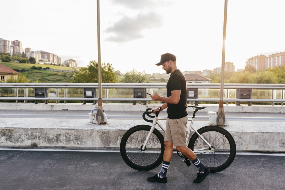 Man walking with bike and using smartphone