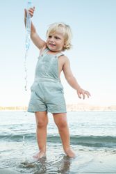Happy little child playing with toy in sea at beach