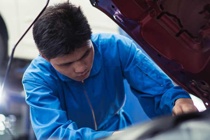 Asian automobile mechanic checking car engine