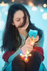 Woman holding gift box and string lights