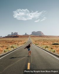 Woman standing in the middle of empty countryside road 4dmYLb